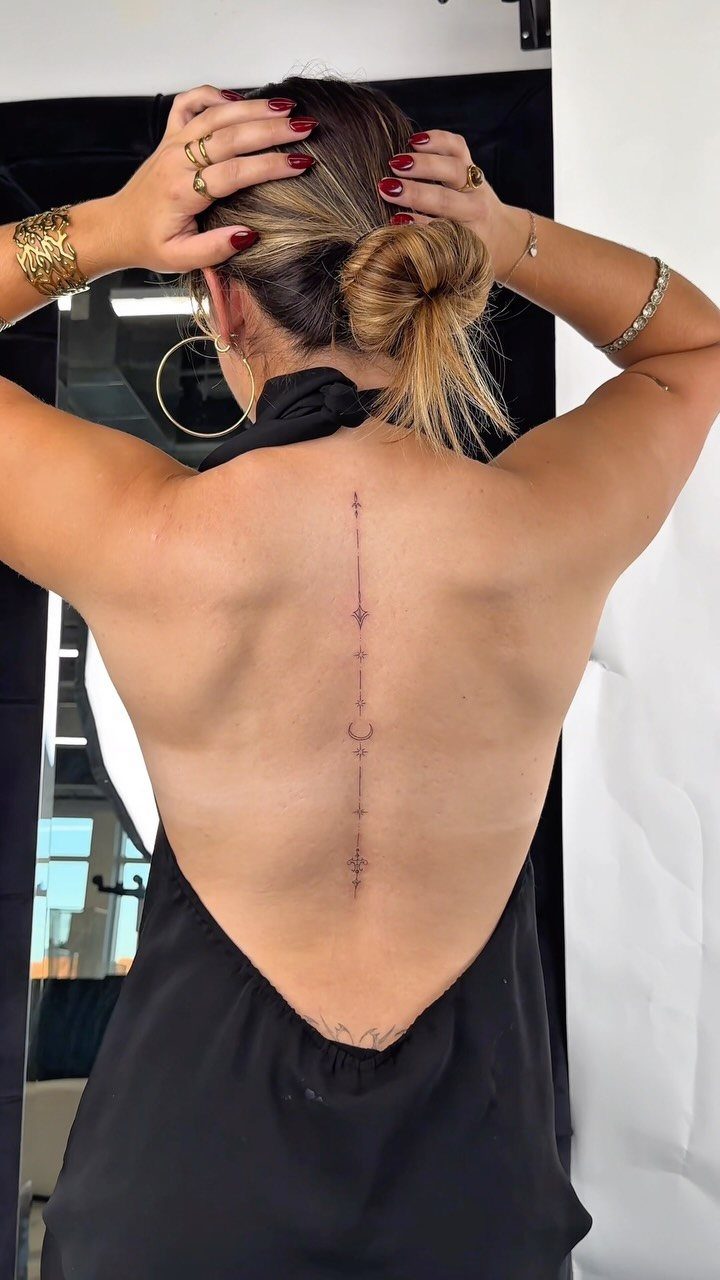 14 Places for a Tattoo for Women: From Ankle to Neck 13 A woman showing a fine-line vertical tattoo running down her spine.