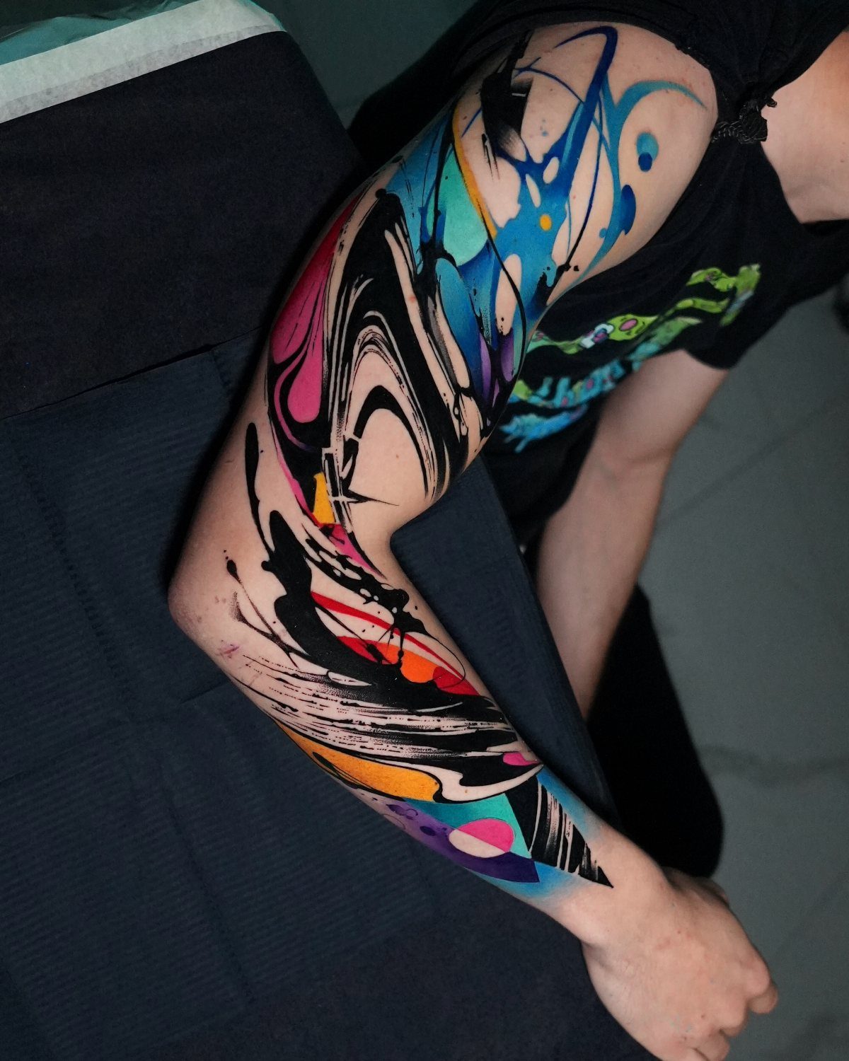 Tattoo Pattern Abstract: 10 Design Ideas for Your Next Ink 9 A person's arm displaying a vibrant, colorful abstract collage style tattoo sleeve.