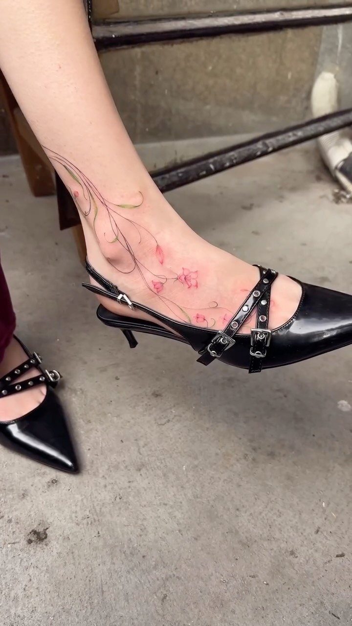 Fine Line Tattoo Placement: 11 Ideas That Actually Work 2 A delicate floral fine line tattoo on a person's foot and ankle wearing black heels.