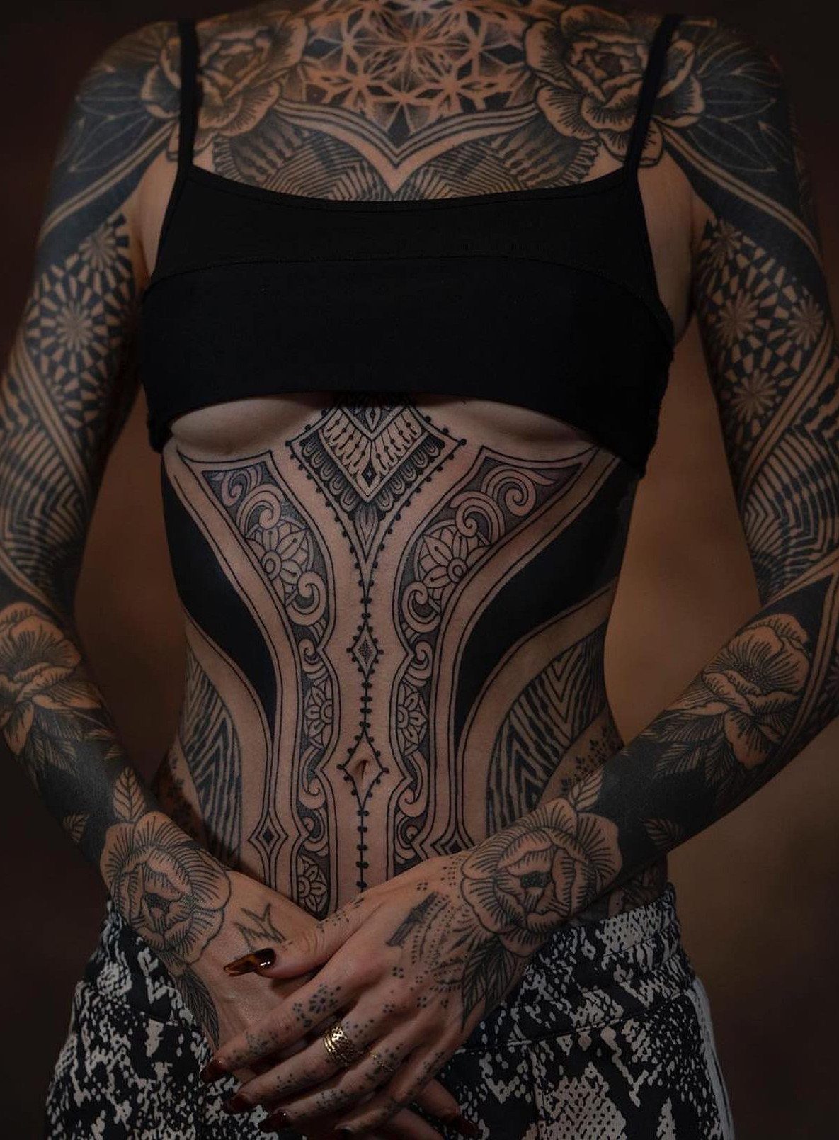 Body Tattoo Design: 5 Styles to Study Before You Book 2 A person with extensive black and gray geometric and floral tattoos covering their arms and torso.