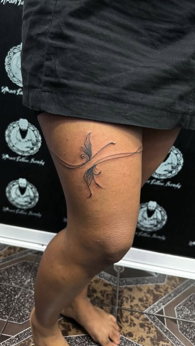Side Thigh Tattoo: 7 Black Ink Designs That Use the Space 5 A black ink fine line vine tattoo with swirls on a person's thigh.