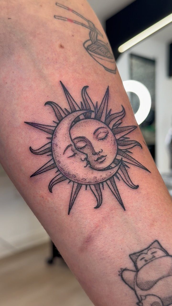 8 Cool Tattoos Ideas Drawing Sketches That Stay Interesting 5 Black ink tattoo of a sun and moon with faces on a person's arm.