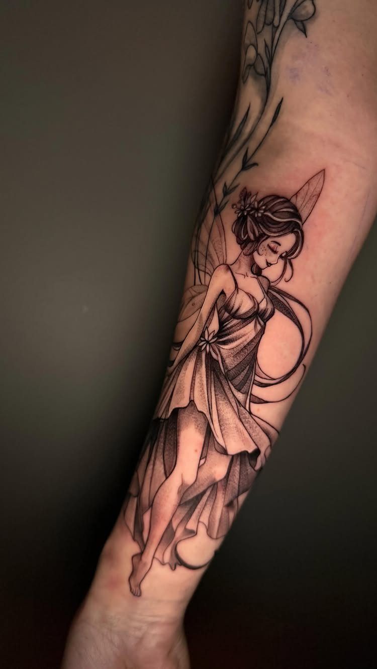 8 Cool Tattoos Ideas Drawing Sketches That Stay Interesting 7 A black ink fairy tattoo with flowing hair and wings on a person's forearm.