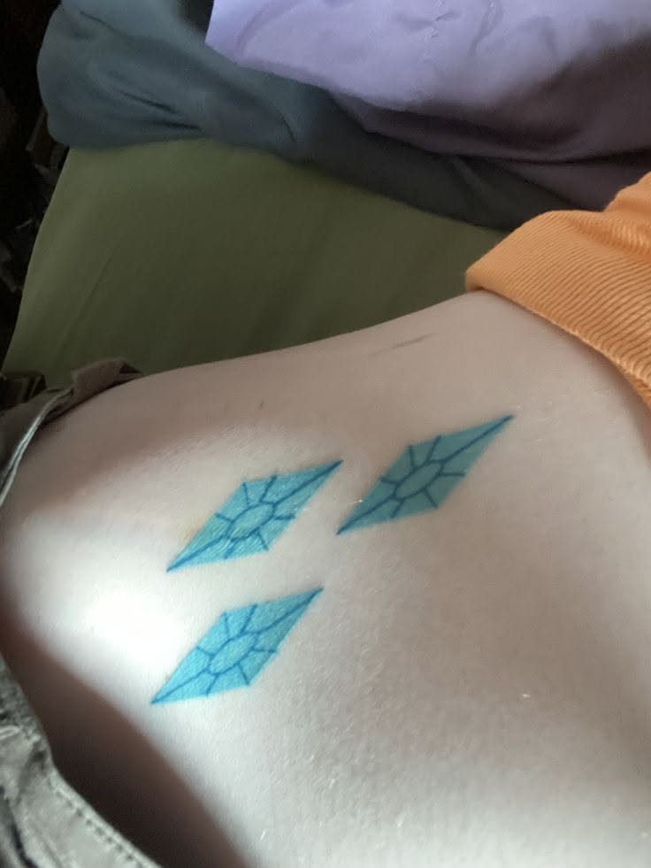 Three light blue diamond tattoos arranged in a cluster on a person's hip skin.