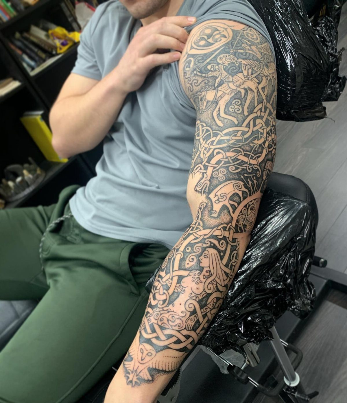 Celtic Pagan Tattoo: 6 Design Ideas and Flash Art 5 A man's arm displaying a large, intricate Celtic knotwork and mythological figure sleeve tattoo.