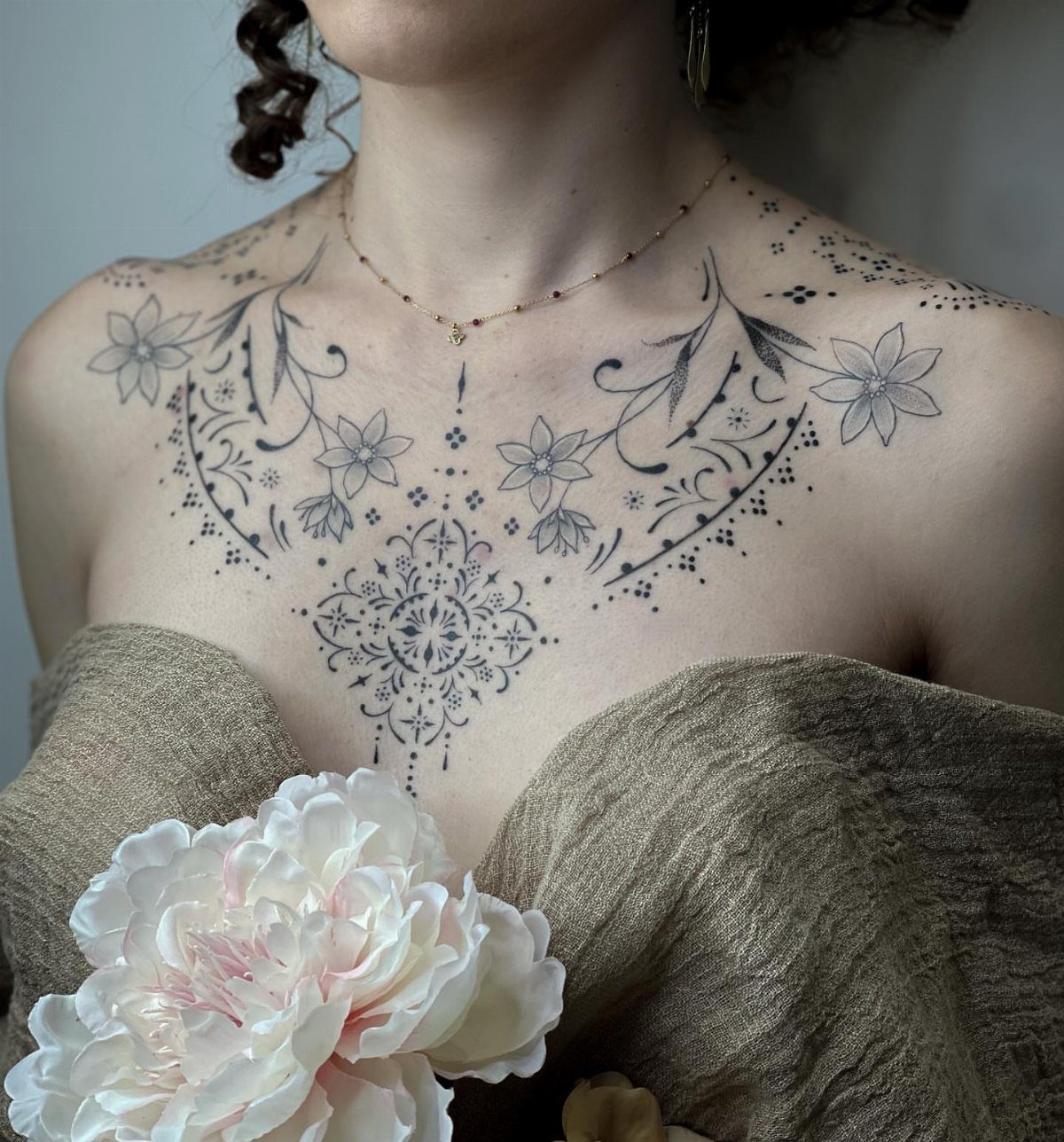 14 Places for a Tattoo for Women: From Ankle to Neck 14 Woman with an intricate floral and mandala tattoo across her chest and collarbones.