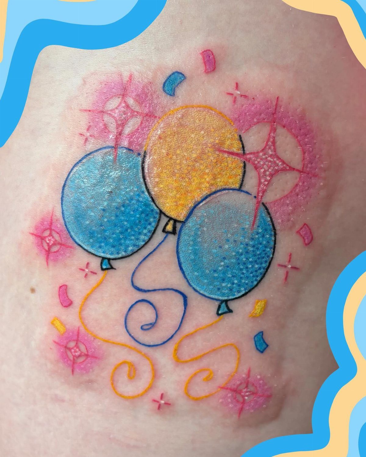 A colorful tattoo of three balloons with swirling ribbons and pink sparkling accents on skin.