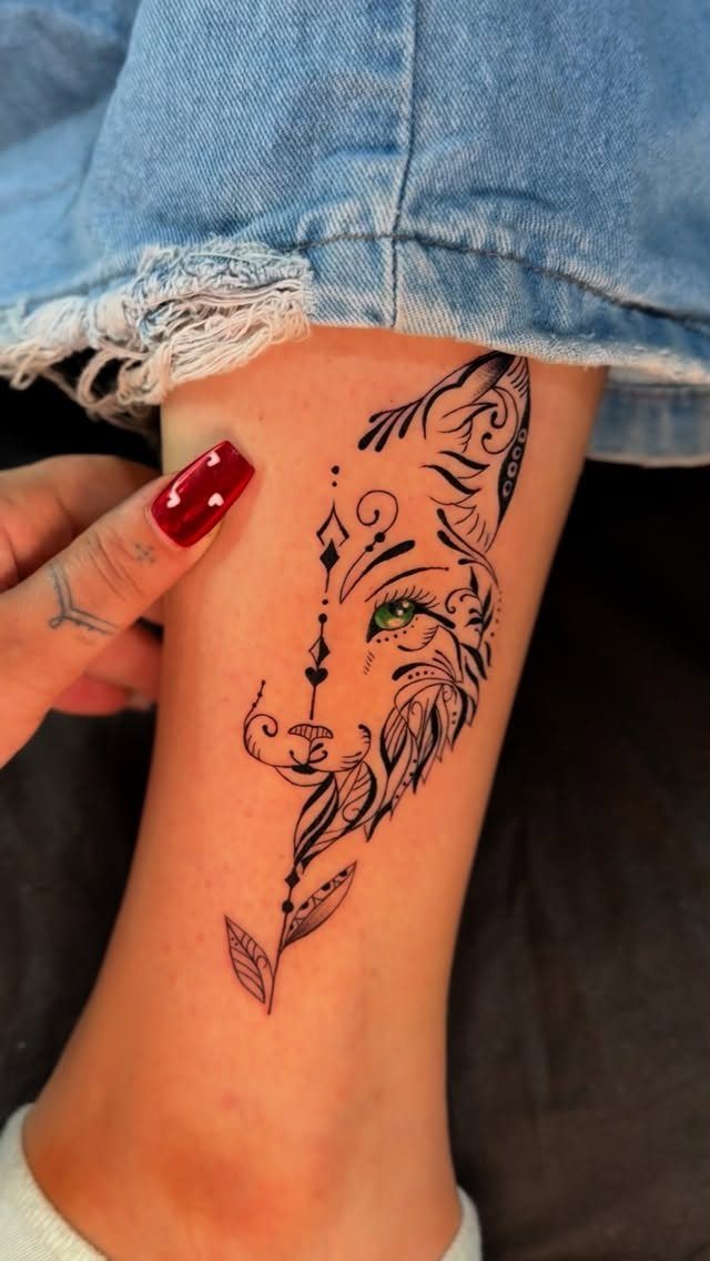 16 Front Ankle Tattoo Ideas for Women 2026 17 A black ink fox head tattoo with decorative patterns on a person's lower leg.