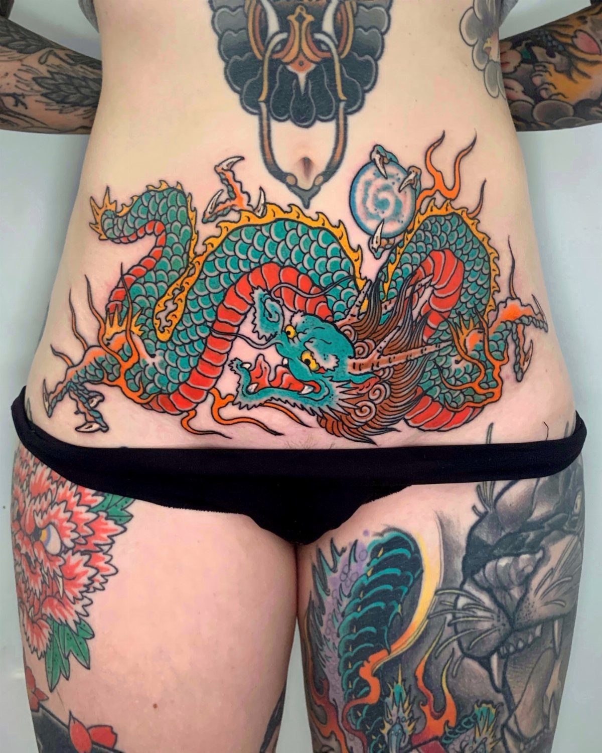 A large colorful dragon tattoo covering a person's stomach and midriff area.