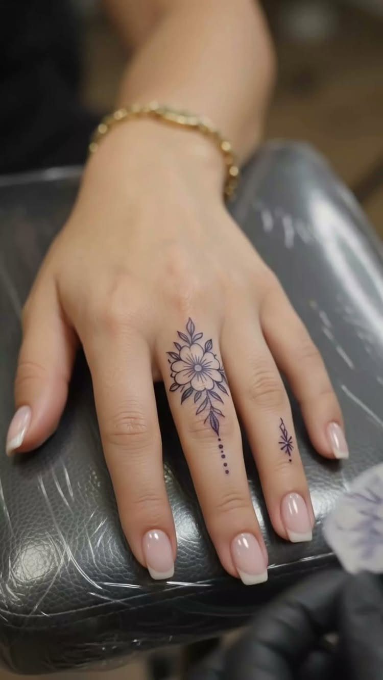 Fine Line Tattoo Placement: 11 Ideas That Actually Work 5 A hand with fine line floral tattoos on the middle and ring fingers.