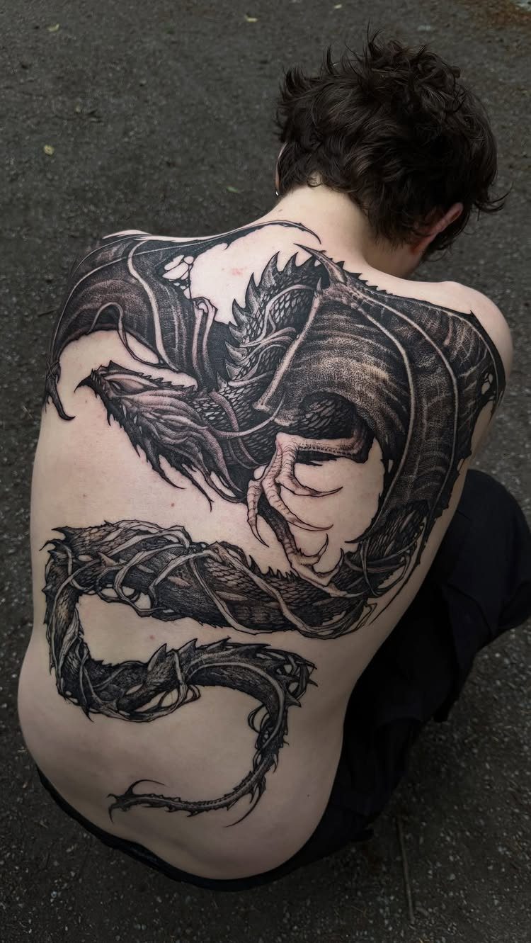 Tattoo Pattern Dragon: 11 Ideas for Ink That Follows the Body 7 A large black ink dragon tattoo covering a person's entire back.