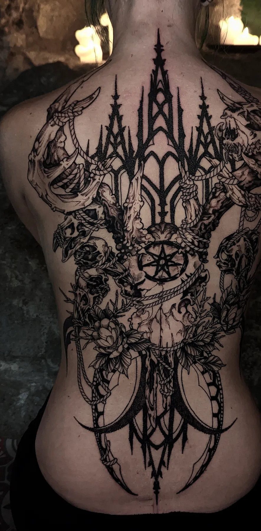 12 Back Tattoo Goth Styles for Spine, Skulls, and Full Backpieces 9 Intricate black ink gothic tattoo covering a person's entire back with skulls and architectural patterns.