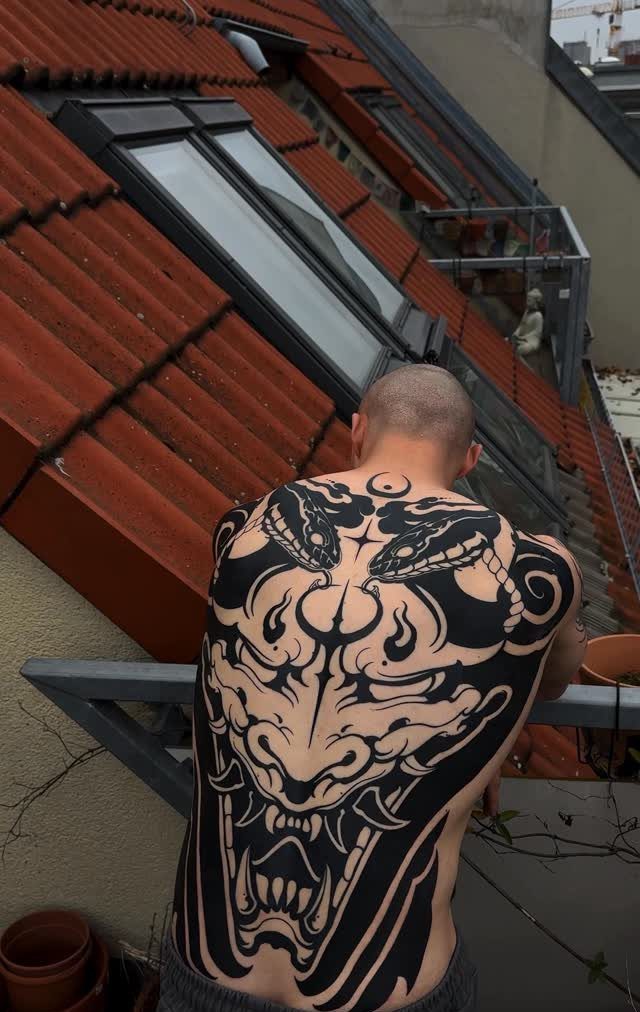 Japanese Tattoo Style: 14 Iconic Motifs and Where They Go 6 A man showing a large black and white Hannya mask tattoo on his back.