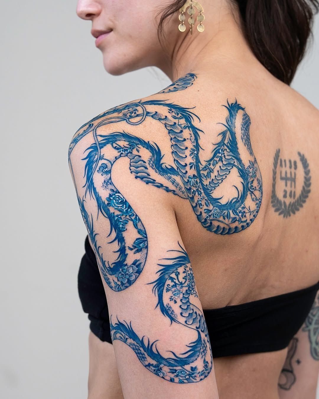 Tattoo Pattern Dragon: 11 Ideas for Ink That Follows the Body 10 A large blue dragon tattoo covering a woman's shoulder, upper arm, and back.