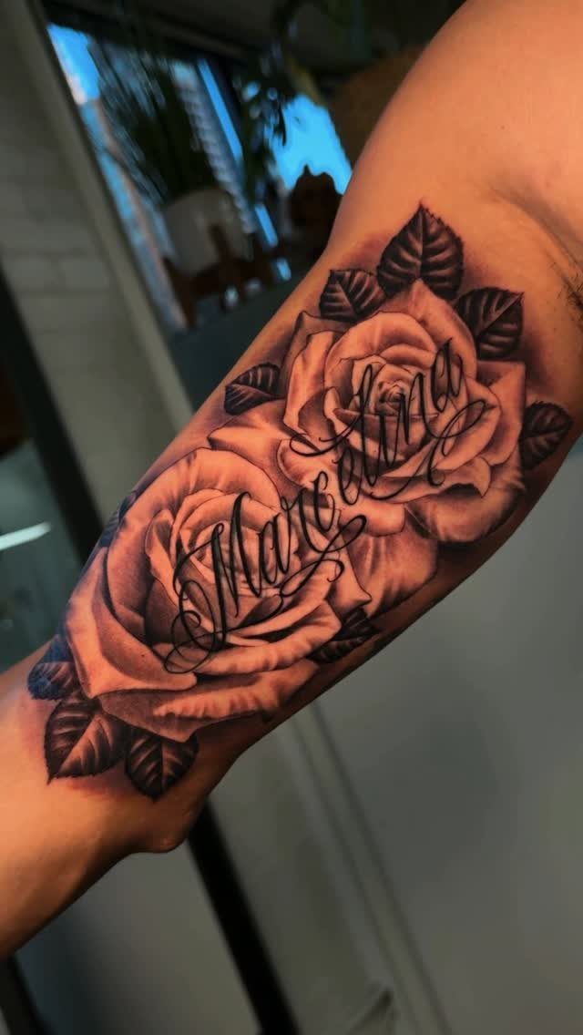 14 Places for a Tattoo for Women: From Ankle to Neck 7 A large black and grey rose tattoo with script text on a person's inner forearm.