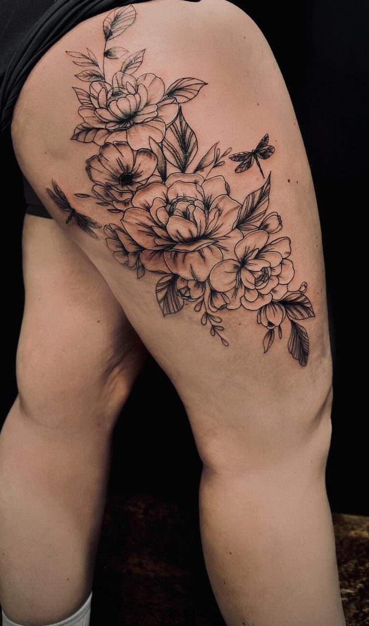 Side Thigh Tattoo: 7 Black Ink Designs That Use the Space 2 Black ink fine line botanical tattoo of peonies and leaves on a person's thigh.