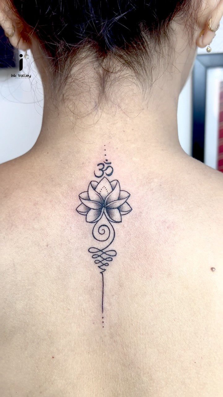 A black ink lotus flower tattoo with symmetrical petals and decorative swirls on a person's neck.