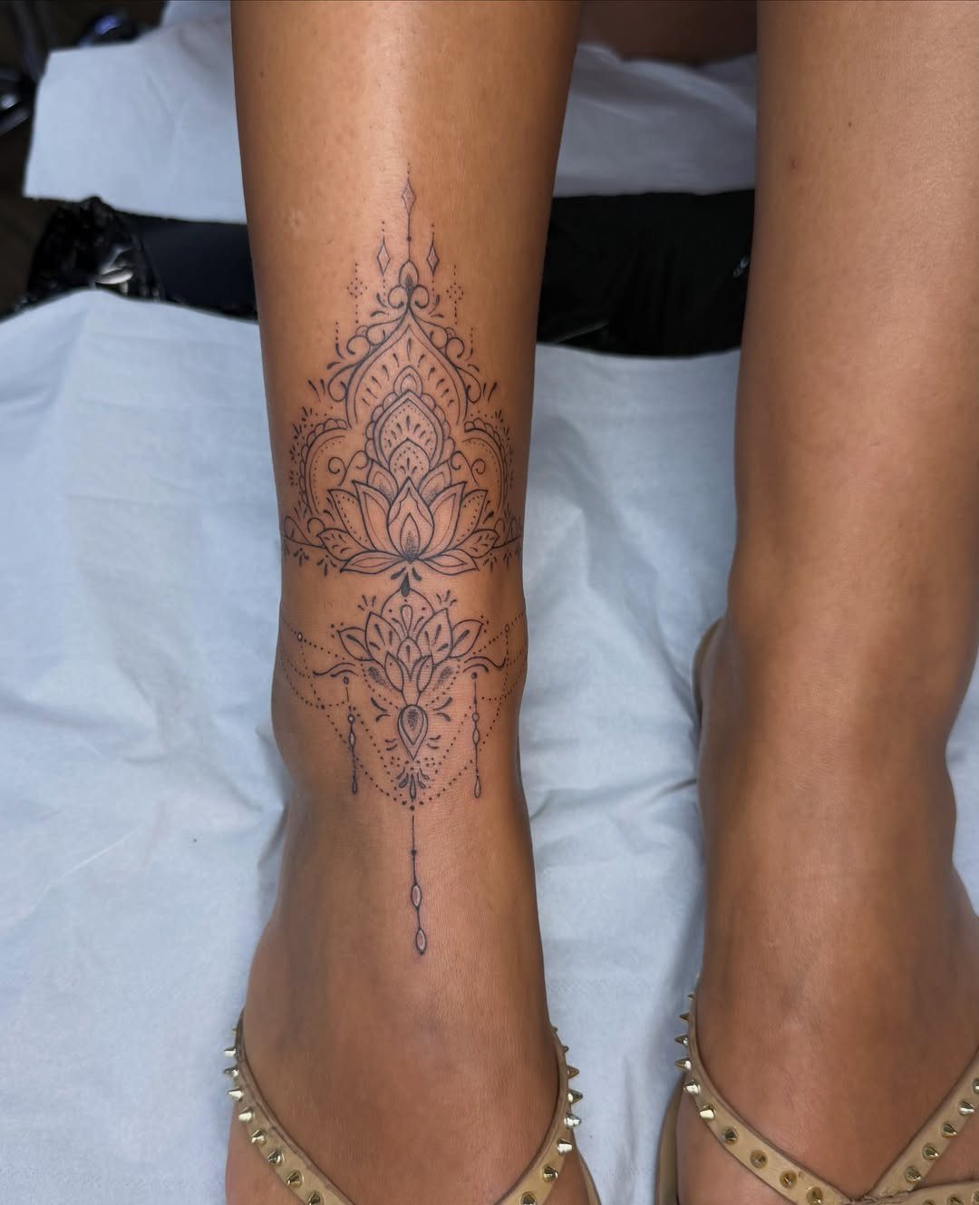 16 Front Ankle Tattoo Ideas for Women 2026 4 Intricate black ink mandala tattoo on a person's lower leg and ankle area.