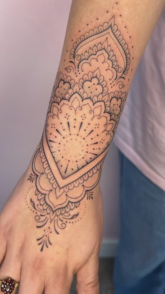 Tattoo Style for Hand: 8 Designs That Work on This Spot 4 A detailed black ink mandala tattoo covering a person's hand and wrist.