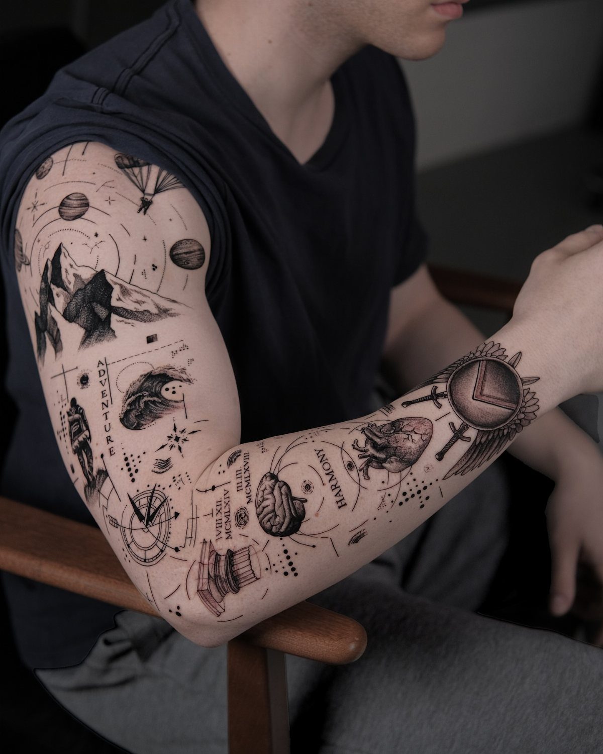 17 Tattoo Pattern on Arm Ideas: From Fine Line to Full Sleeve 3 A person's arm covered in a detailed black and grey sleeve tattoo with various miniature illustrations.