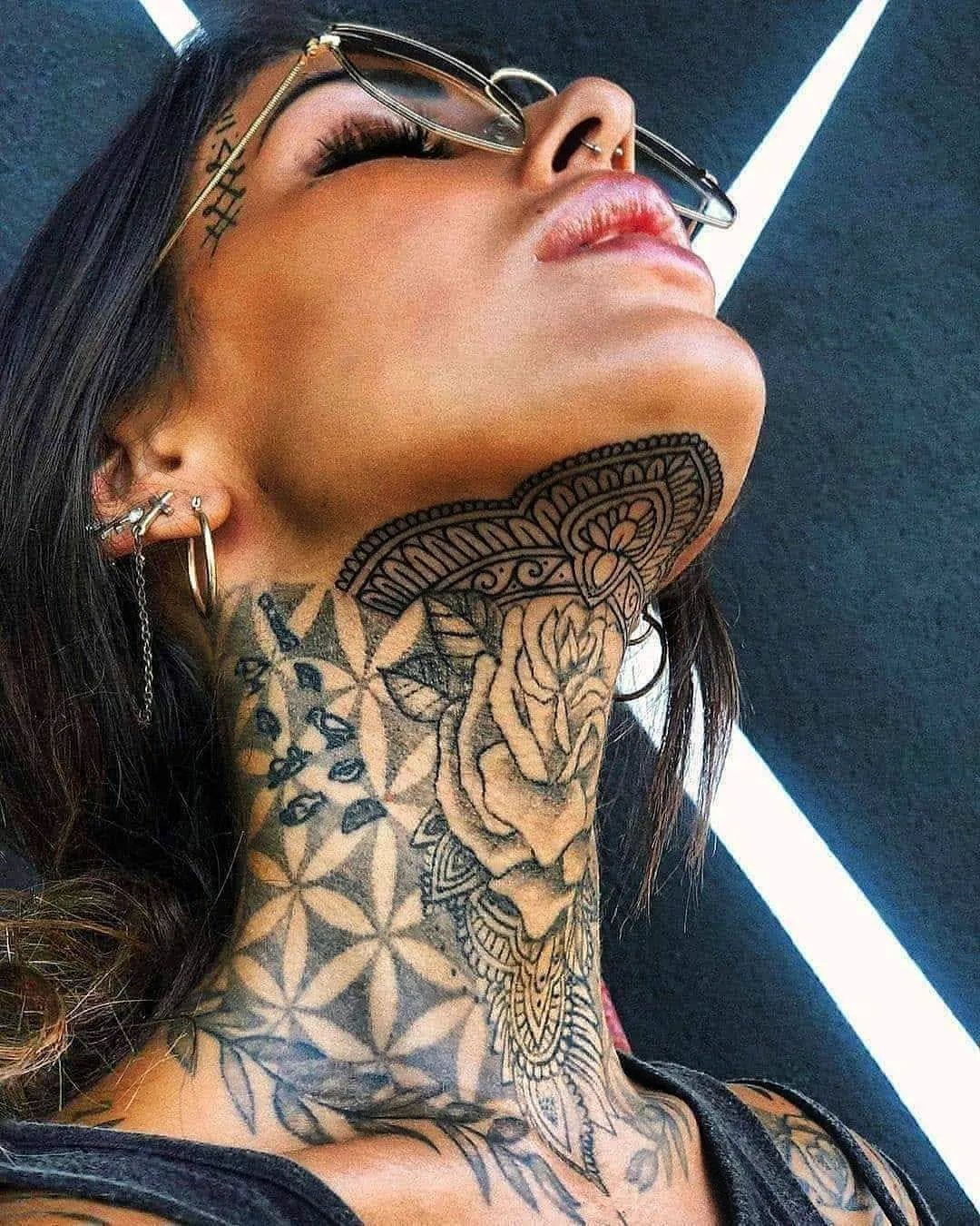 14 Places for a Tattoo for Women: From Ankle to Neck 15 A woman with large, intricate black ink floral and geometric tattoos covering her neck.