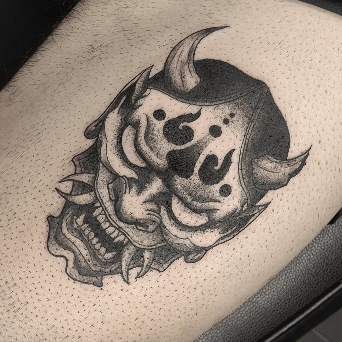 Japanese Tattoo Style: 14 Iconic Motifs and Where They Go 14 A black and grey Oni mask tattoo on a person's skin.