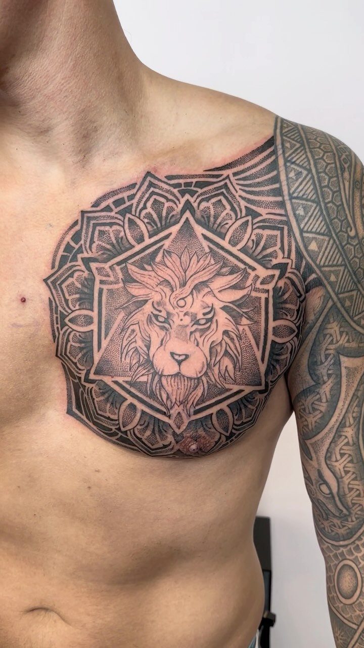 Tattoo at Chest: 15 Ideas from Wing Spread to Underboob 8 A large lion and mandala tattoo covering a man's left pectoral muscle and shoulder.