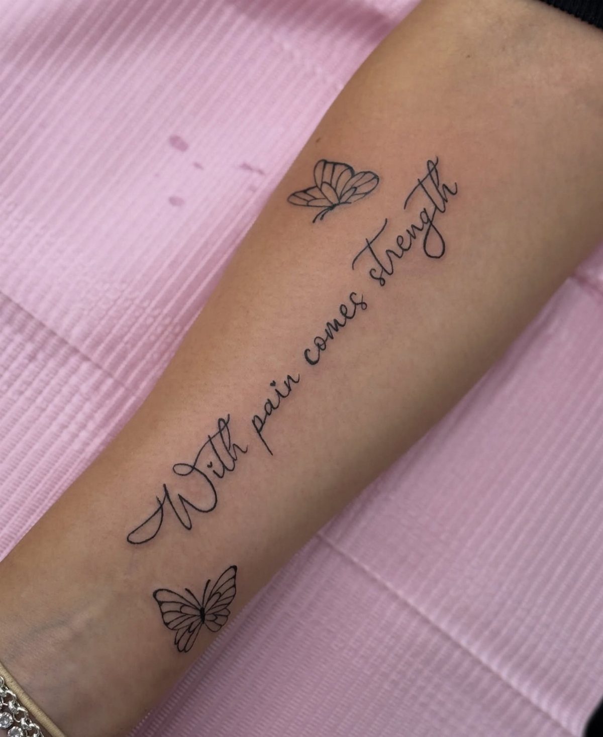 11 Tattoo Arm Women Will Want to See Before Booking 2026 12 A forearm tattoo with the quote 'With pain comes strength' and two small butterflies.