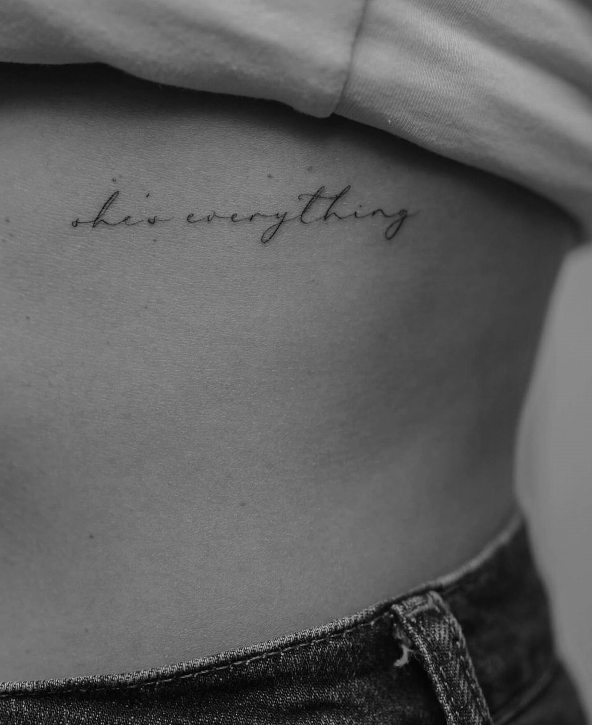 Fine Line Tattoo Placement: 11 Ideas That Actually Work 11 A fine line script tattoo reading 'she's everything' on a person's ribcage.