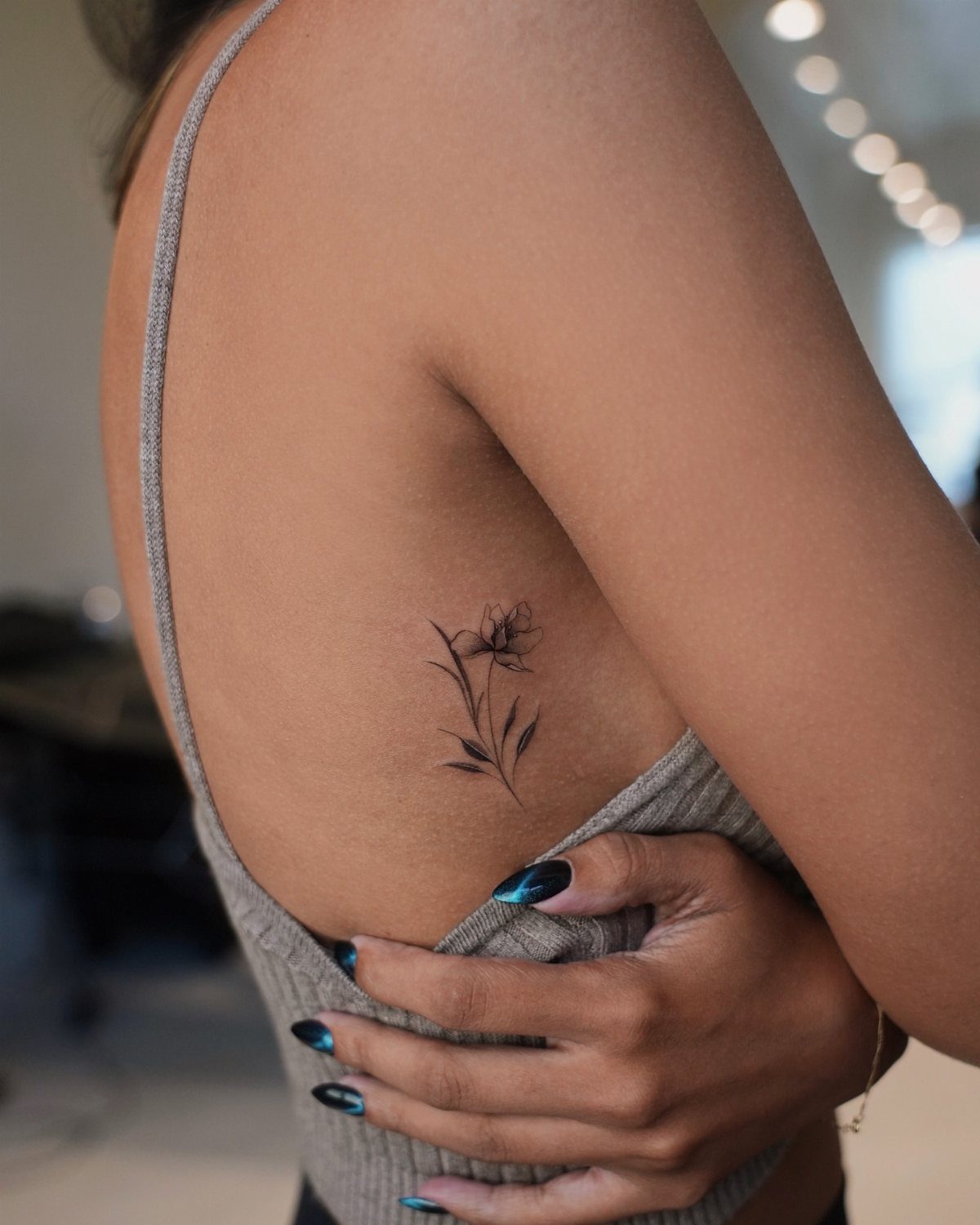 14 Places for a Tattoo for Women: From Ankle to Neck 10 A delicate black ink floral tattoo on a woman's ribcage side.