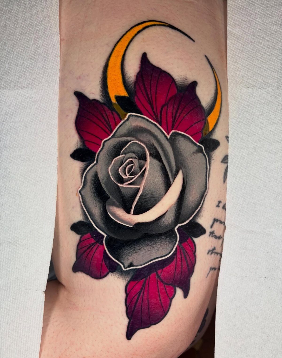 17 Tattoo Pattern on Arm Ideas: From Fine Line to Full Sleeve 12 A large rose tattoo with red leaves and a yellow crescent moon on a person's arm.