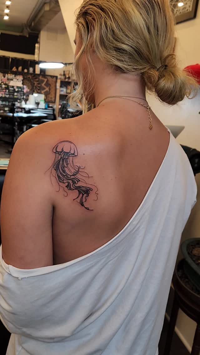 Tattoo Placement on Back: 6 Areas for Your Next Ink 2 A woman with a black ink jellyfish tattoo on her right shoulder blade.