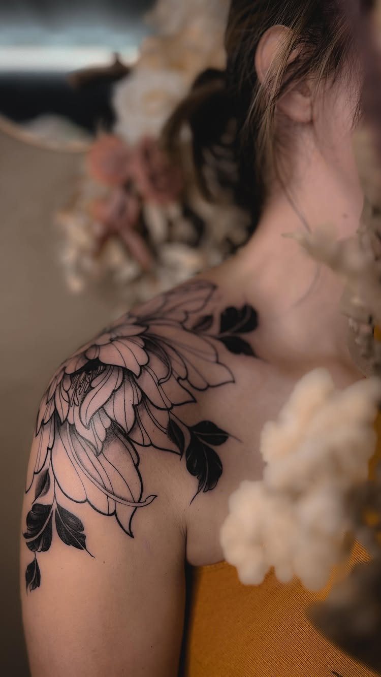 14 Places for a Tattoo for Women: From Ankle to Neck 2 A large black floral tattoo covering a woman's shoulder and upper arm area.