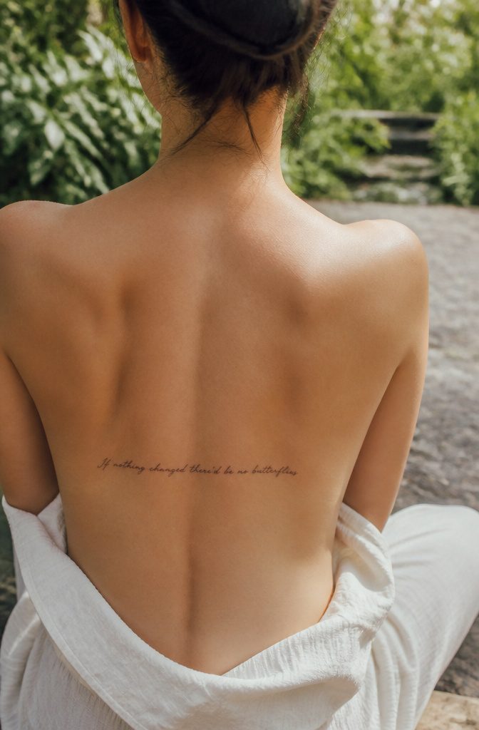 Spine Tattoo Quotes: Ideas for Women, Men and Small Lettering 3 Tattoo of a small phrase in cursive on the upper back.