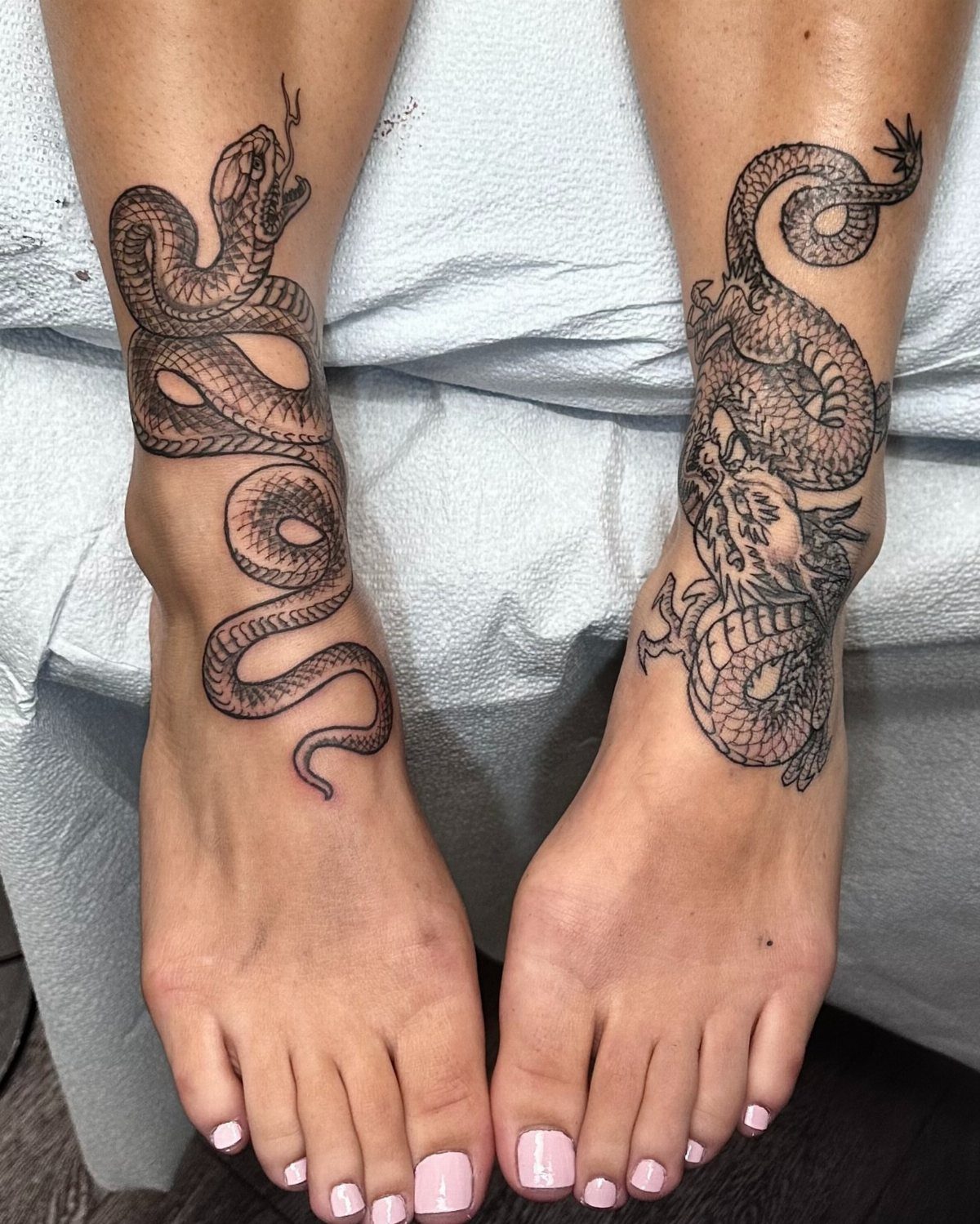 16 Front Ankle Tattoo Ideas for Women 2026 14 Two feet with black ink snake tattoos on the ankles and lower legs.
