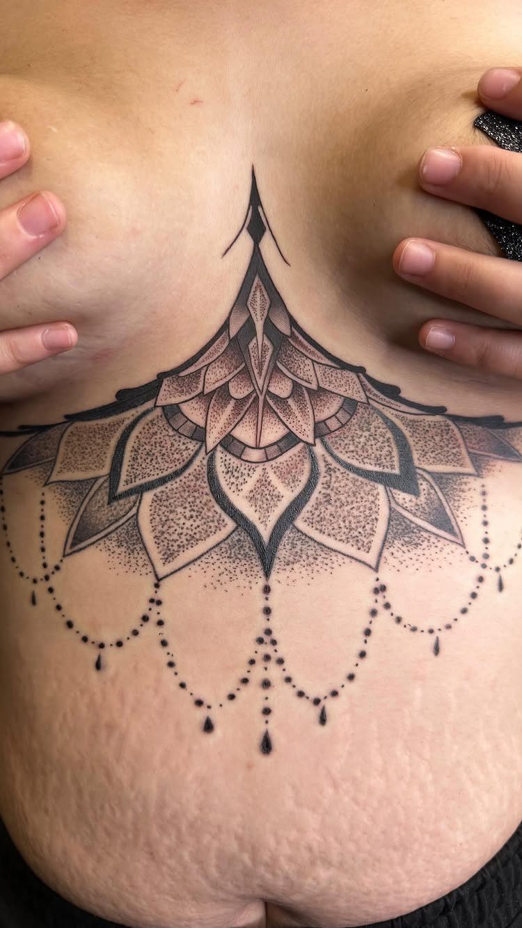 Tattoo at Chest: 15 Ideas from Wing Spread to Underboob 4 A large symmetrical mandala tattoo with hanging bead patterns on a person's sternum.