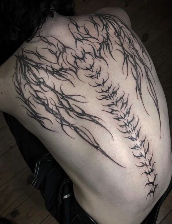 12 Back Tattoo Goth Styles for Spine, Skulls, and Full Backpieces 8 Black ink symmetrical thorny patterns tattooed across a person's upper and lower back.