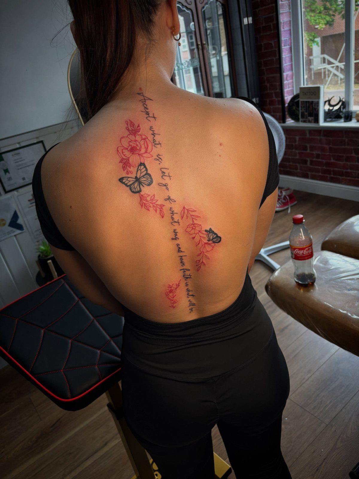 A woman with a vertical floral and script tattoo running down her spine.