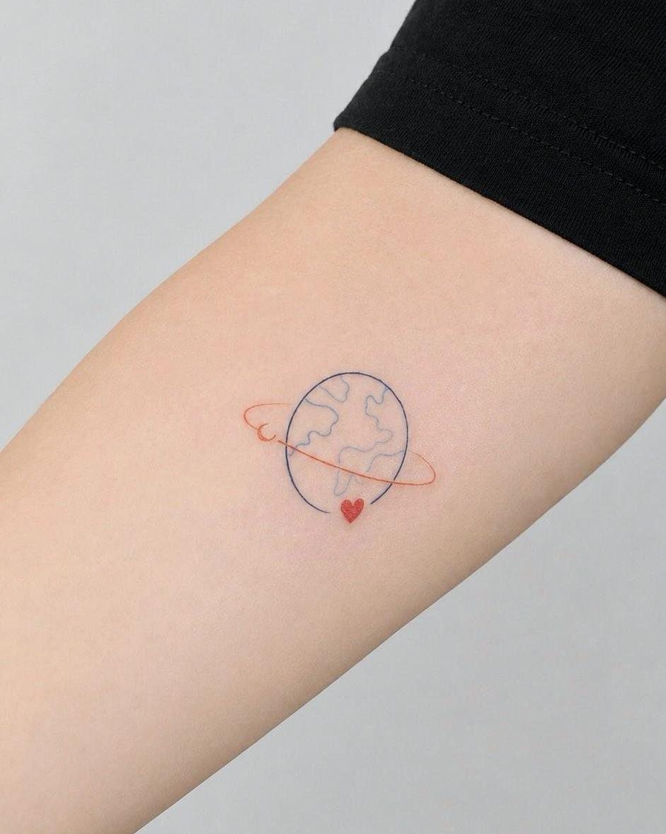 A minimalist tiny earth tattoo with a red ring and heart on a person's arm.