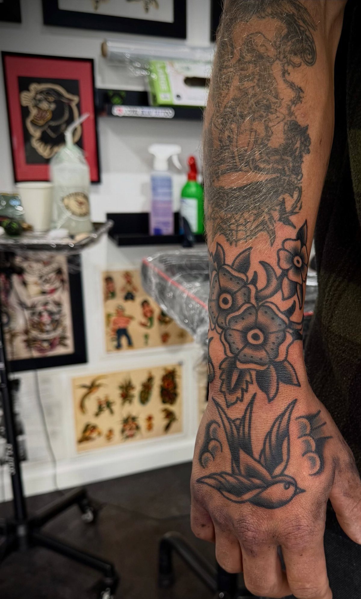 Tattoo Style for Hand: 8 Designs That Work on This Spot 6 A person's hand and forearm displaying various black ink traditional style tattoos.