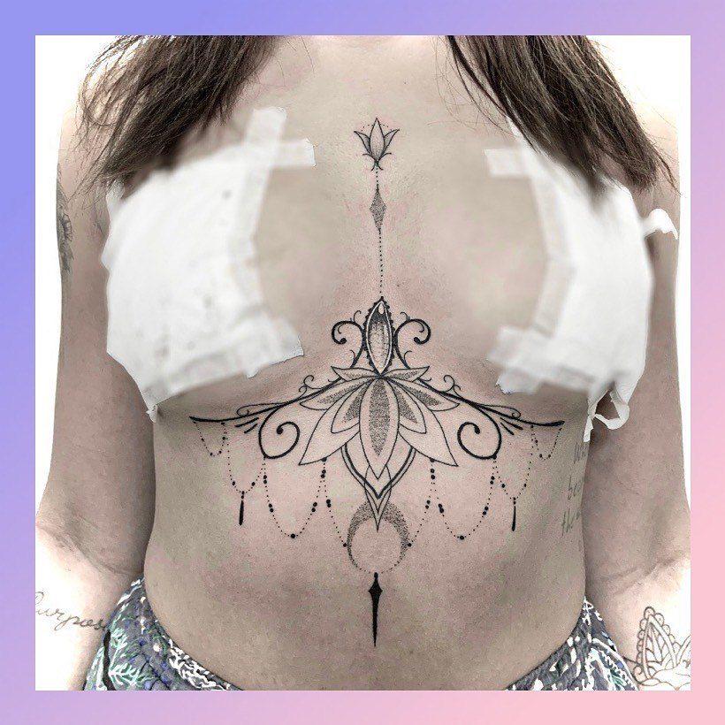 Tattoo at Chest: 15 Ideas from Wing Spread to Underboob 16 Symmetrical black ink mandala tattoo with fine line details on a person's torso.