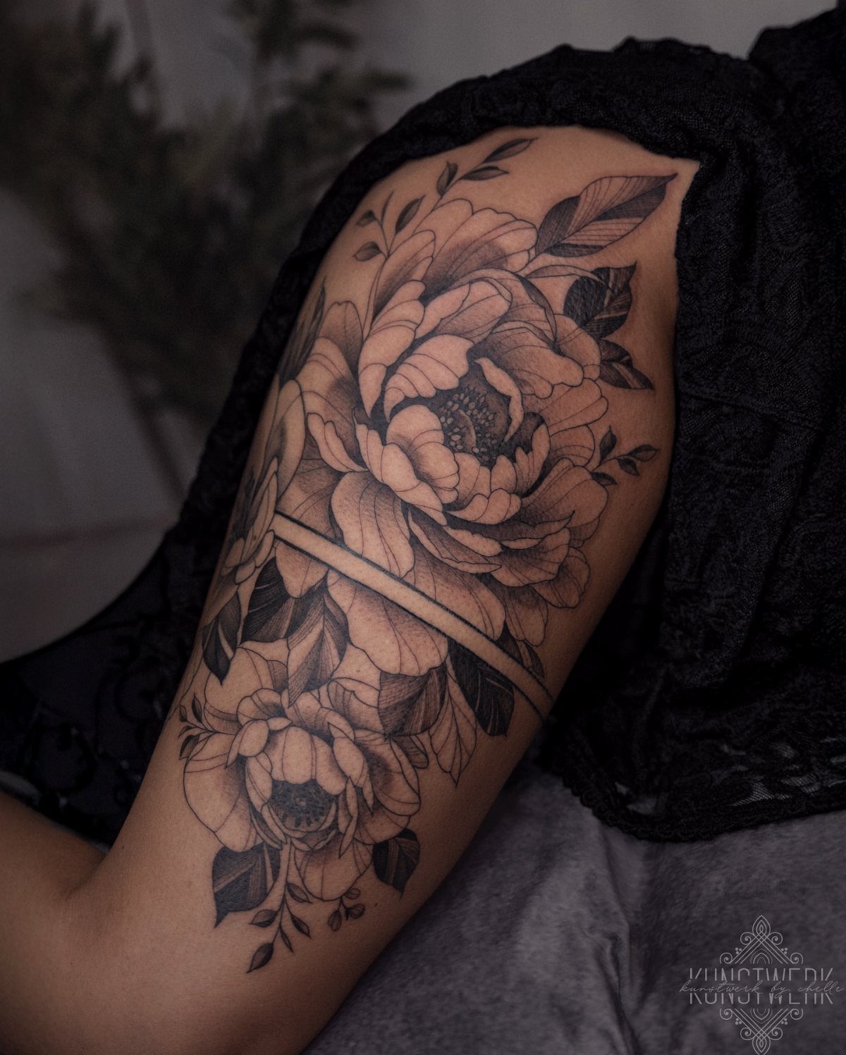14 Places for a Tattoo for Women: From Ankle to Neck 11 Large black and grey peony floral tattoo on a person's upper arm.
