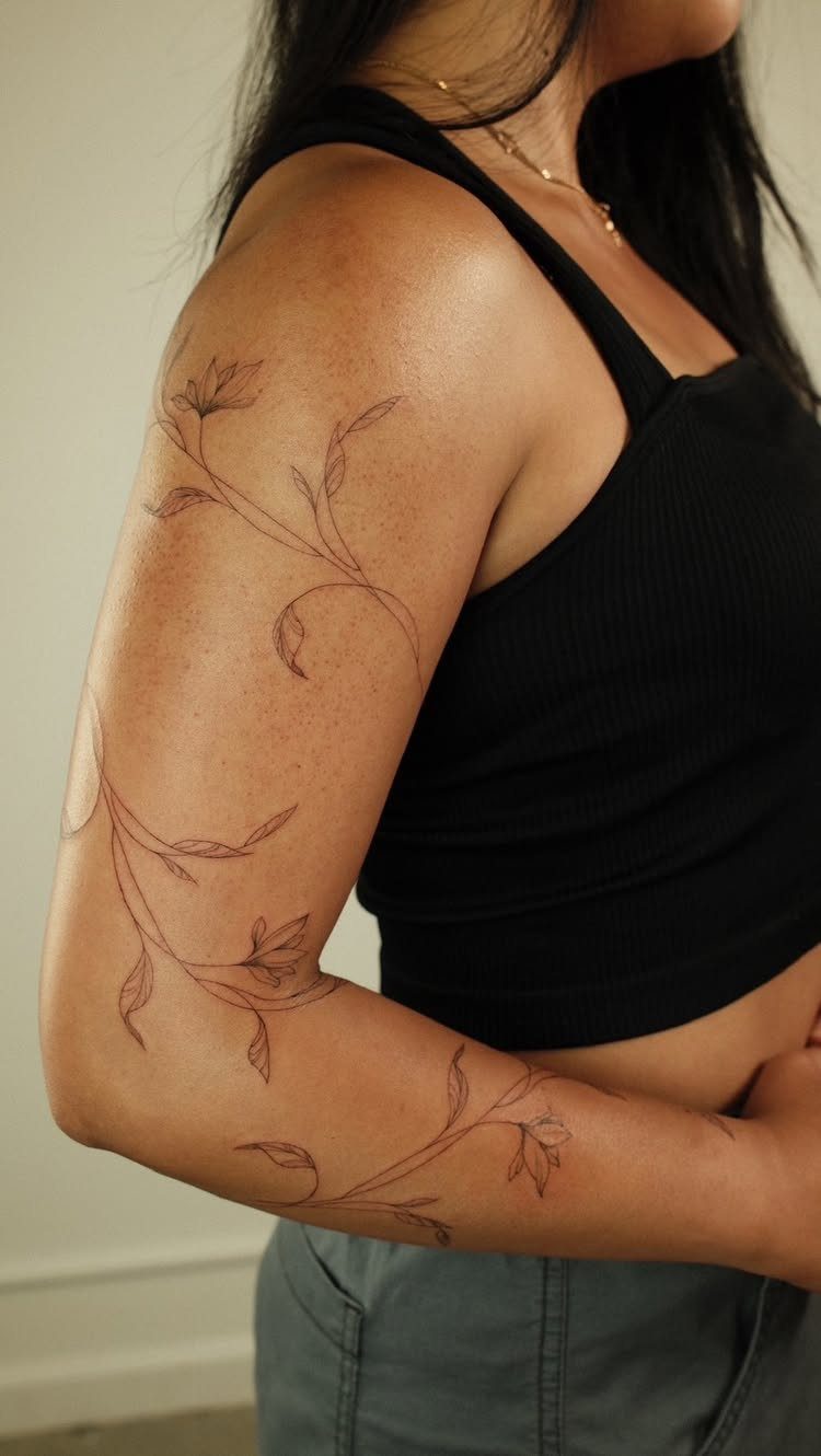 11 Tattoo Arm Women Will Want to See Before Booking 2026 8 A woman's arm decorated with a delicate fine-line vine and leaf tattoo.